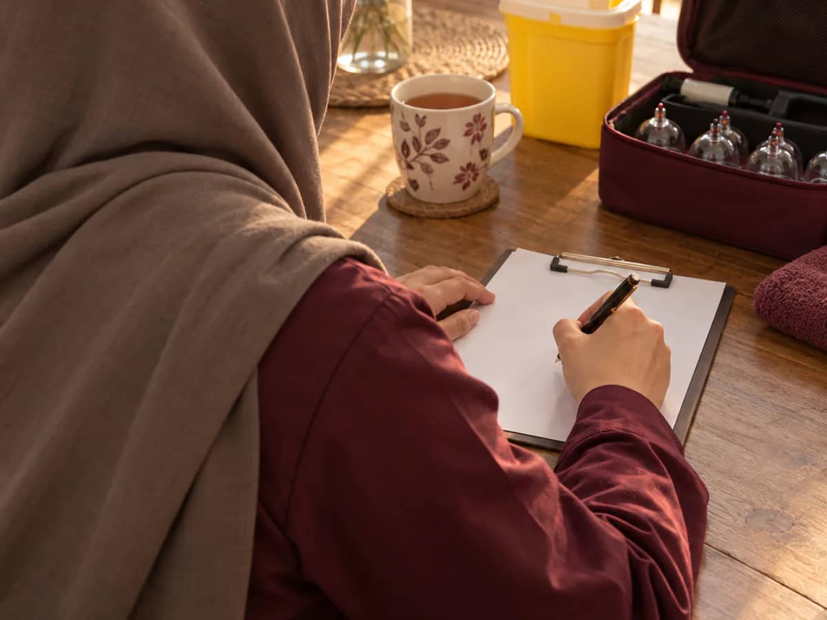 Aftercare notes, a cup of tea and a sealed sharps container on a kitchen table