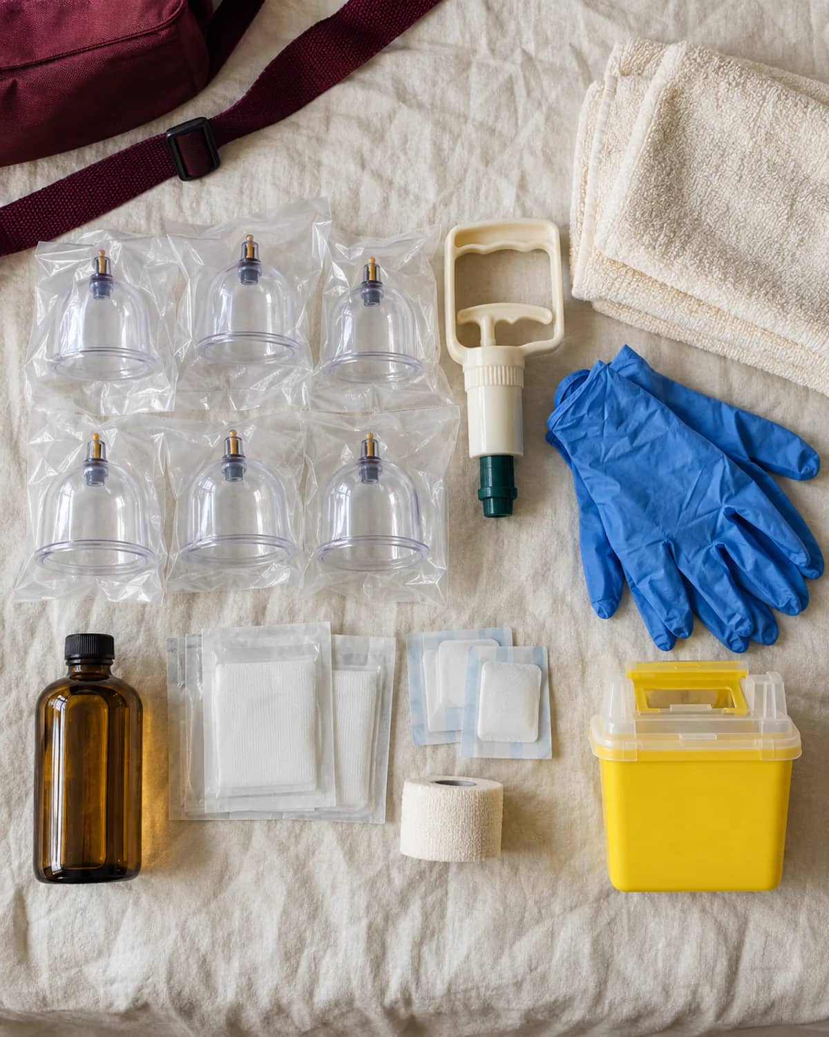 Flat-lay of a mobile cupping kit with sealed cups, pump, gloves, dressings and a sharps container
